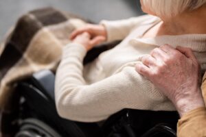 Hand on the shoulder of older woman in wheelchair