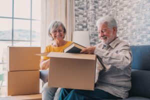 Senior couple smiling as they pack books into boxes